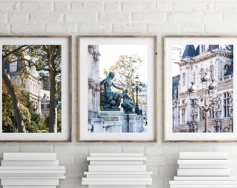 May include: Three framed photographs of a Parisian building with a statue, trees, and a street lamp. The building is white with ornate details and the statue is bronze.