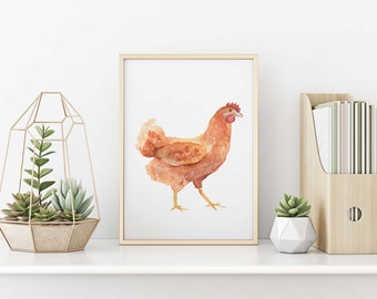 Puede incluir: Una pintura de acuarela de una gallina marrón con cresta y barbillas rojas. La gallina está de pie sobre un fondo blanco. La pintura está enmarcada en un marco de madera claro.
