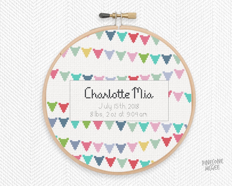 Peut inclure: Un cerceau de broderie blanc avec un motif de guirlande color&eacute; et le texte "Charlotte Mia, 15 juillet 2018, 8 lbs, 2 oz &agrave; 9h04".