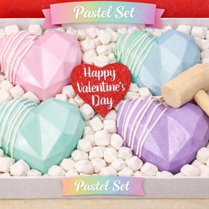 May include: A pastel-colored heart-shaped chocolate set for Valentine's Day. The set includes pink, mint green, and purple chocolates, a red heart with the text "Happy Valentine's Day", and a wooden mallet. The chocolates are in a white box with marshmallows.