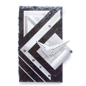 May include: Abstract black and white wall clock with geometric design. The clock face features a textured black background with white lines and numbers. A 3D element with a folded paper design is attached to the clock face.