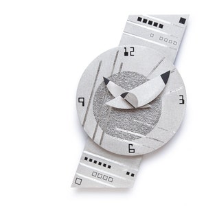 May include: A modern, abstract wall clock in shades of gray and white. The clock face is circular with black numerals and hands. The design includes geometric shapes and lines, creating a unique, artistic timepiece.