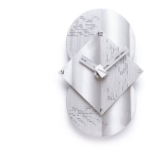 May include: A modern, silver-toned wall clock with a unique design. The clock features a square face and two circular elements, with the numbers 12 and 9 visible. The clock hands are thin and rectangular. The clock is made of metal.