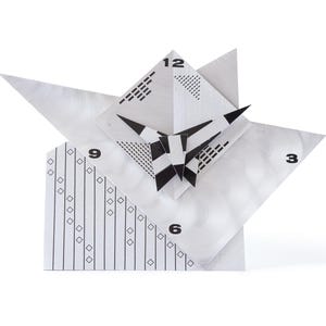 May include: A modern, geometric clock with a white and silver finish. The clock face features black numerals at 3, 6, 9, and 12 o'clock. The design incorporates angular shapes and a black and white geometric pattern.