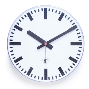 Puede incluir: Un reloj redondo blanco con manecillas y marcadores de hora negros. La esfera del reloj tiene un diseño minimalista con un segundero rojo y un logotipo en la parte inferior. El reloj es probablemente para montaje en pared.