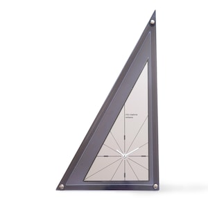 May include: A silver triangle-shaped clock with a white face and black hands. The clock has a silver frame and a silver base. The clock is on a white background.