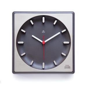 May include: Square wall clock with a dark gray face and a silver-colored frame. The clock has white hands, a red second hand, and a minimalist design. The clock face has a circular design with white markers. The words "TIME LINE" are printed on the bottom right.