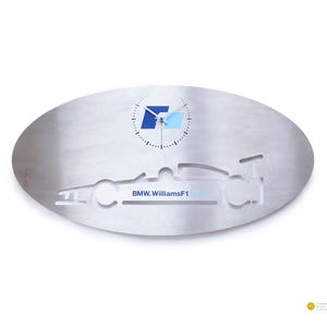 Könnte beinhalten: Ovale Wanduhr aus Metall mit gebürsteter Oberfläche. Die Uhr hat oben ein blau-weißes BMW-Logo und unten eine ausgeschnittene Silhouette eines Rennwagens. Der Text "BMW.WilliamsF1" ist sichtbar.