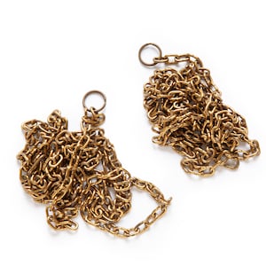 May include: Two gold-colored chains with a ring at the end of each chain. The chains are tangled and lying on a white surface.