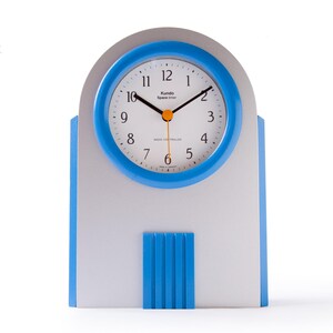 May include: A silver and blue analog clock with a white face and black hands. The clock has a Kundo Space Timer label and is radio controlled.