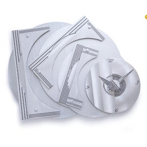 May include: A modern, abstract wall clock with a silver finish. The clock features a circular clock face with hands and a unique design of overlapping shapes and dotted lines. The words "Vintage German Clocks" are in the upper right corner.