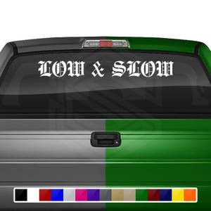 Puede incluir: Una camioneta blanca con una ventana trasera verde. La ventana trasera tiene una calcomanía blanca que dice "LOW & SLOW" en letras antiguas.