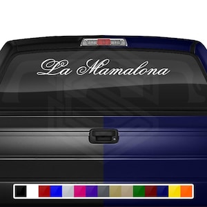 May include: A white decal with the text "La Mamalona" applied to the rear window of a black and blue pickup truck.