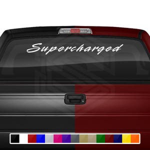 May include: White vinyl decal with the word "Supercharged" in a cursive font. The decal is applied to the rear window of a black and red pickup truck. The decal is available in a variety of colors.