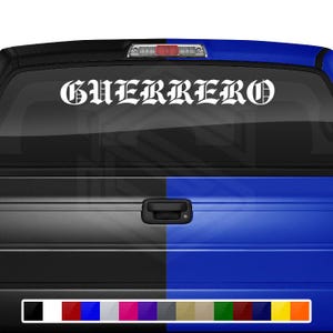 May include: White vinyl decal with the word "GUERRERO" in a gothic font, displayed on the rear window of a truck. The truck's body is split between black and blue panels, with a selection of color swatches at the bottom.