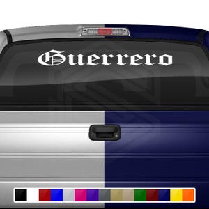 May include: White vinyl decal with the word "Guerrero" in a gothic font style, applied to the rear window of a pickup truck. The truck is painted half white and half blue.