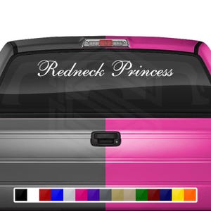 以下が含まれることがあります： ピンクとグレーのテールゲートが付いた白いトラック。テールゲートには「Redneck Princess」と書かれた白いステッカーが貼られています。