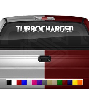 Puede incluir: Calcomanía blanca con el texto "TURBOCHARGED" en una fuente de goteo, aplicada en la ventana trasera de una camioneta roja y blanca.