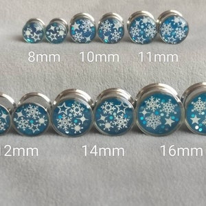 May include: Set of 10 silver ear gauges with blue and white snowflake designs. The gauges are 8mm, 10mm, 11mm, 12mm, 14mm, and 16mm in size.