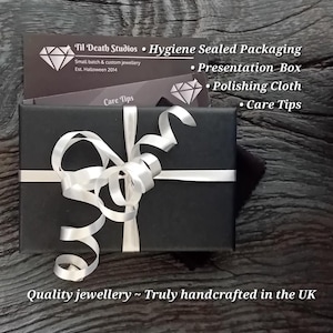 Puede incluir: Una caja de regalo negra atada con una cinta de sat&eacute;n blanca. La caja contiene joyas y es de Til Death Studios. El texto en la caja dice "Quality jewellery ~ Truly handcrafted in the UK."