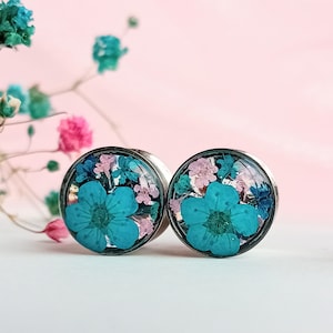 May include: A pair of silver ear gauges with a floral design. The gauges feature a mix of blue, pink, and green pressed flowers.