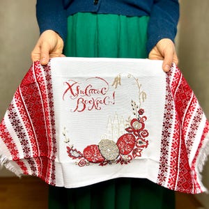 May include: White embroidered cloth with red and white trim. The embroidery features a church, flowers, and the text "Христос Воскрес!" in Cyrillic.