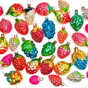 May include: A collection of vintage glass Christmas ornaments shaped like various fruits and berries, including raspberries, strawberries, and grapes in vibrant colors like red, green, blue, yellow, and silver with metallic finishes.