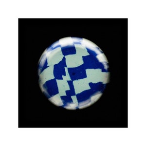 May include: A round, blue and white patterned ceramic tile with a checkerboard design.