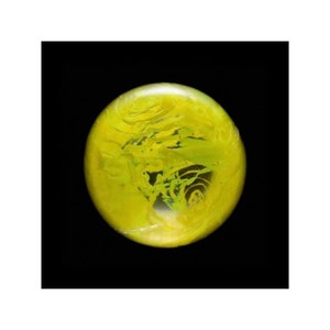 May include: A yellow glass sphere with swirling green and white patterns inside. The sphere is on a black background.
