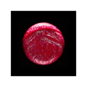 May include: A close-up of a red, round, textured object with a white rim. The object is isolated against a black background.