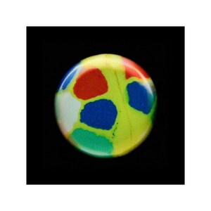 May include: A round, yellow, green, blue, red, and white marble with a swirling pattern.
