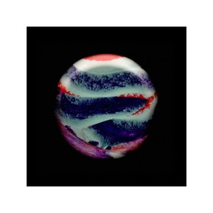 May include: A close-up of a round, colorful marble with swirls of blue, purple, pink, and white paint.