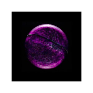 May include: A close-up of a round, purple, and black marble with a shiny, textured surface.