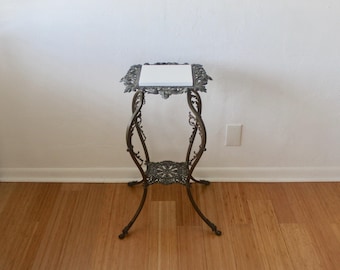 Pode incluir: Uma mesa com tampo de mármore branco e base de latão adornada. A mesa tem um tampo quadrado e quatro pernas com detalhes intrincados.