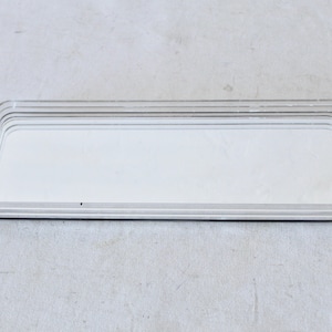May include: A clear acrylic tray with a mirrored surface. The tray has a rectangular shape and is made of multiple layers of acrylic.