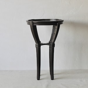 May include: A black metal side table with a round top and four legs. The table has a hammered metal finish.