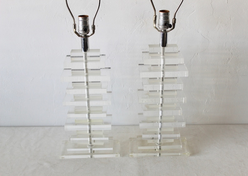 May include: Two clear acrylic lamps with a stacked design. Each lamp has a silver metal base and a clear glass shade.