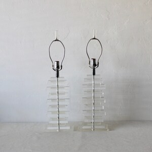 May include: A pair of clear acrylic table lamps with stacked rectangular bases and chrome lampshades.