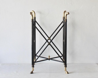 May include: A black metal table with brass accents and four legs. The table has a simple, geometric design and is perfect for a small space.