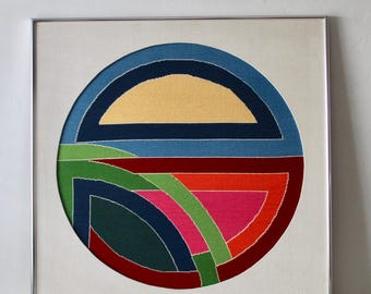 Pode incluir: Uma obra de arte abstrata emoldurada com um design circular que apresenta uma variedade de cores, incluindo vermelho, verde, azul, amarelo e rosa.