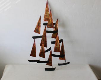 Pode incluir: Uma escultura de parede feita de metal com um design em camadas de veleiros. Os veleiros são pintados em tons de cobre e marrom com detalhes pretos.