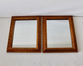 Pode incluir: Dois espelhos retangulares com moldura de madeira adornada e acabamento dourado. Os espelhos têm uma moldura decorativa.