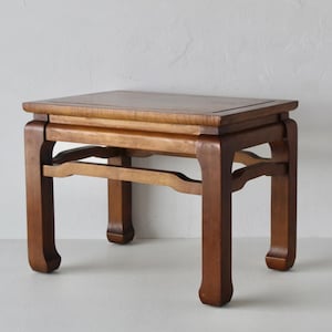 May include: A rectangular wooden side table with a smooth, polished brown finish. The table features four sturdy, slightly curved legs connected by horizontal support bars on all sides, creating a stable base for the flat, rectangular tabletop surface.