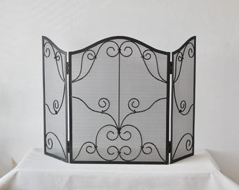 Pode incluir: Tela de lareira de metal preto com um design de três painéis. A tela apresenta um design ornamentado e enrolado em cada painel. A tela de malha é emoldurada por uma borda decorativa. A tela foi projetada para ficar em pé sozinha.