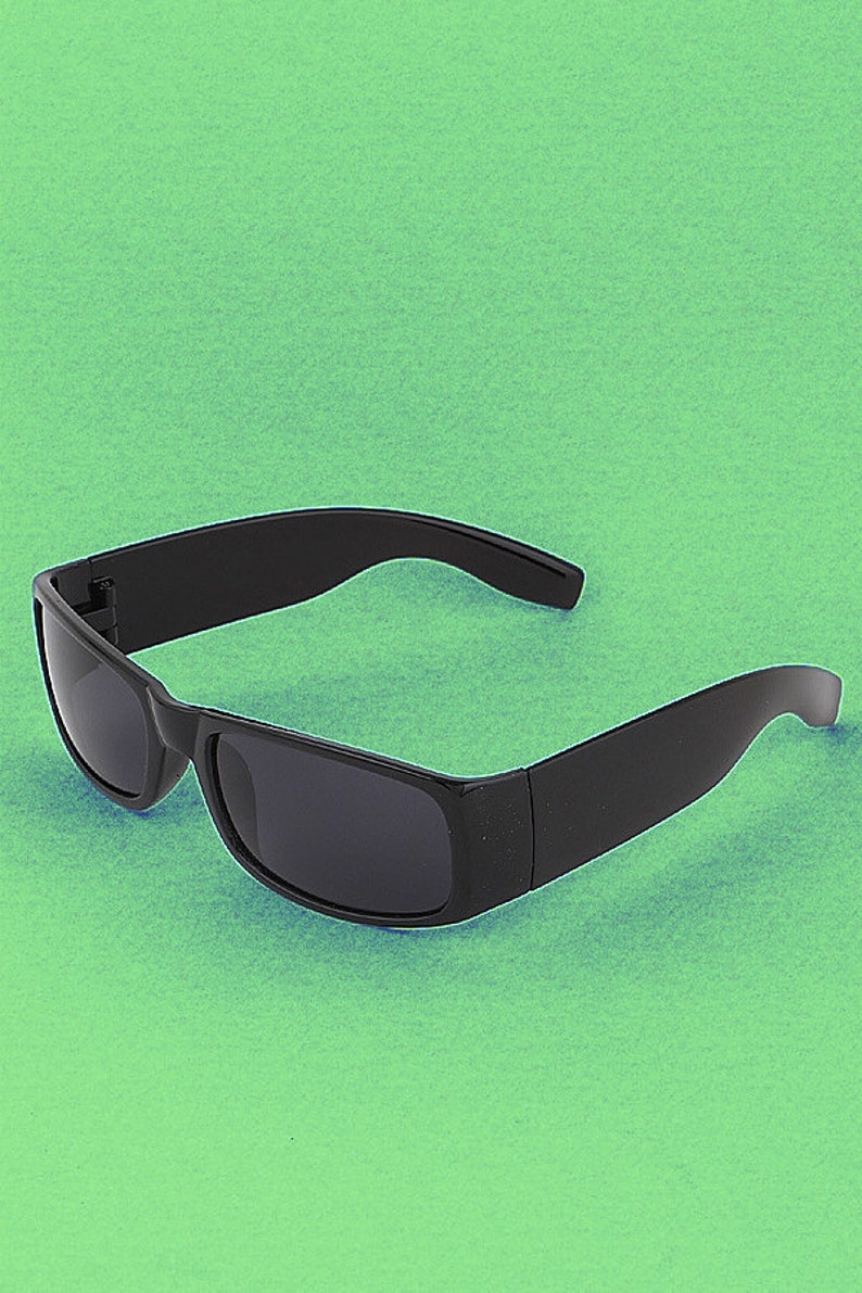 Puede incluir: Gafas de sol negras con montura rectangular y lentes oscuras.