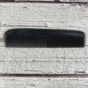 May include: A black comb with fine teeth, featuring the word "Unbreakable" embossed on the top. The comb is made of a solid, durable material and is designed for hair grooming.