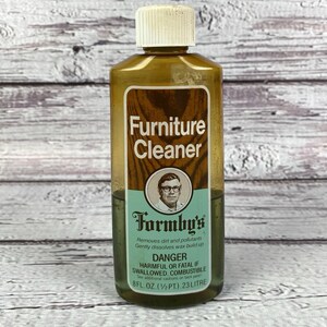 May include: A bottle of Formby's Furniture Cleaner with a white cap. The label reads "Furniture Cleaner" and "Formby's". The bottle contains 8 fl oz (1/2 pt) or 23 liters of liquid. The label also warns of danger.