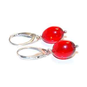 Puede incluir: Un par de pendientes de plata con cuentas ovaladas de vidrio rojo.