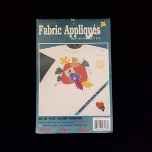 May include: A package for a fabric applique kit. The kit features a design of a patchwork pumpkin with leaves and flowers. The package has the words "Fabric Appliqués" and "Patchwork Pumpkin" printed on it.