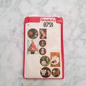 May include: Simplicity sewing pattern number 8721 for making Christmas ornaments. The pattern includes instructions for making a snowman, a stocking, a gingerbread man, a Christmas tree, and an angel ornament.